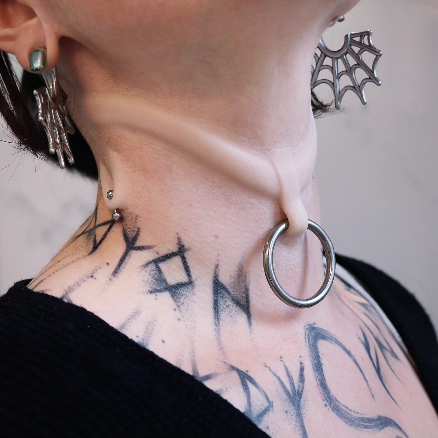 Woman's neck with a stretched piercing and subdermal choker prosthetic