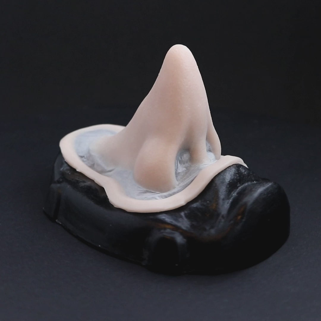 Short pointy nose prosthetic in vanilla shade on a black turntable, slowly rotating.