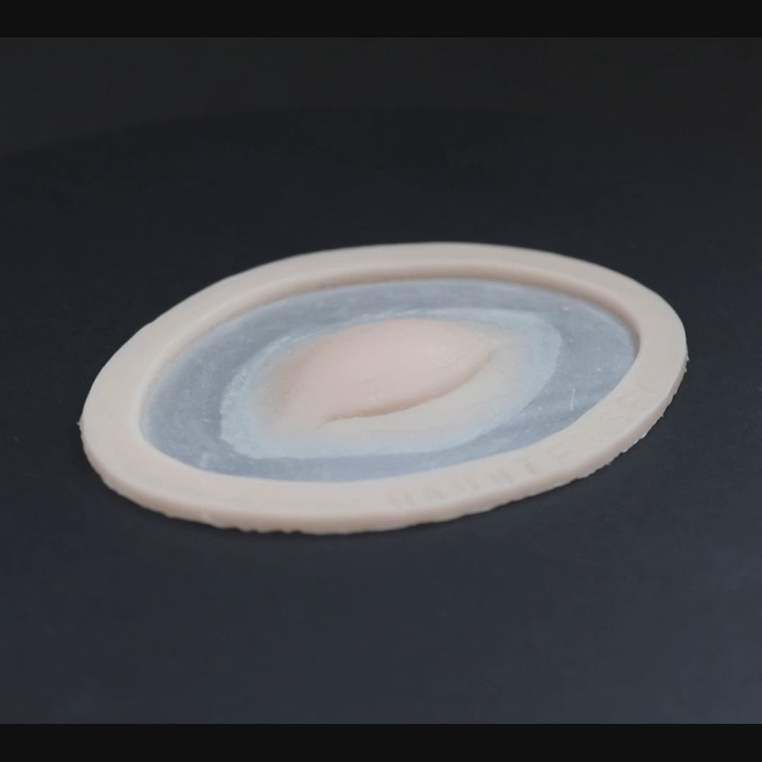 Closed Third Eye prosthetic in vanilla shade on a black turntable, slowly rotating.