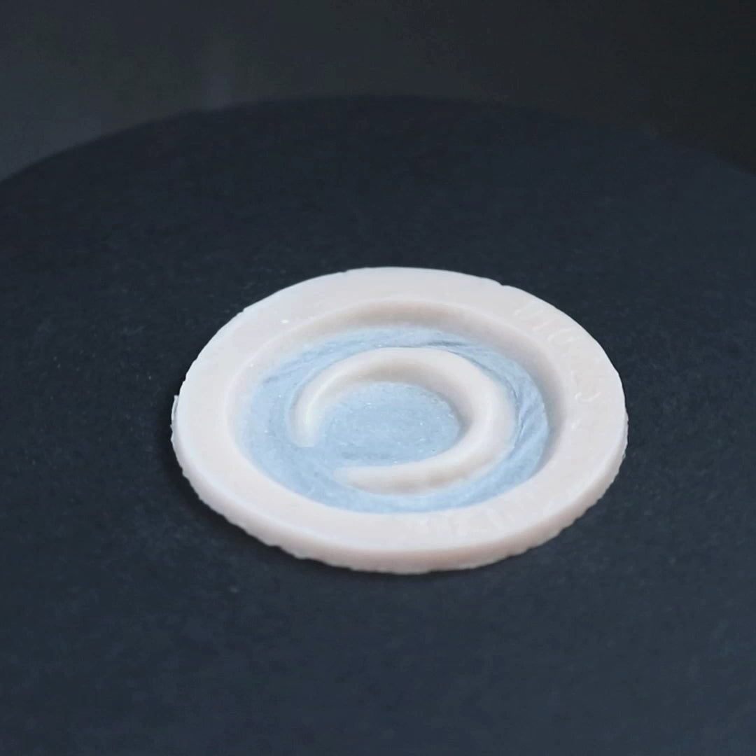 Small moon prosthetic in vanilla shade on a black turntable, slowly rotating.
