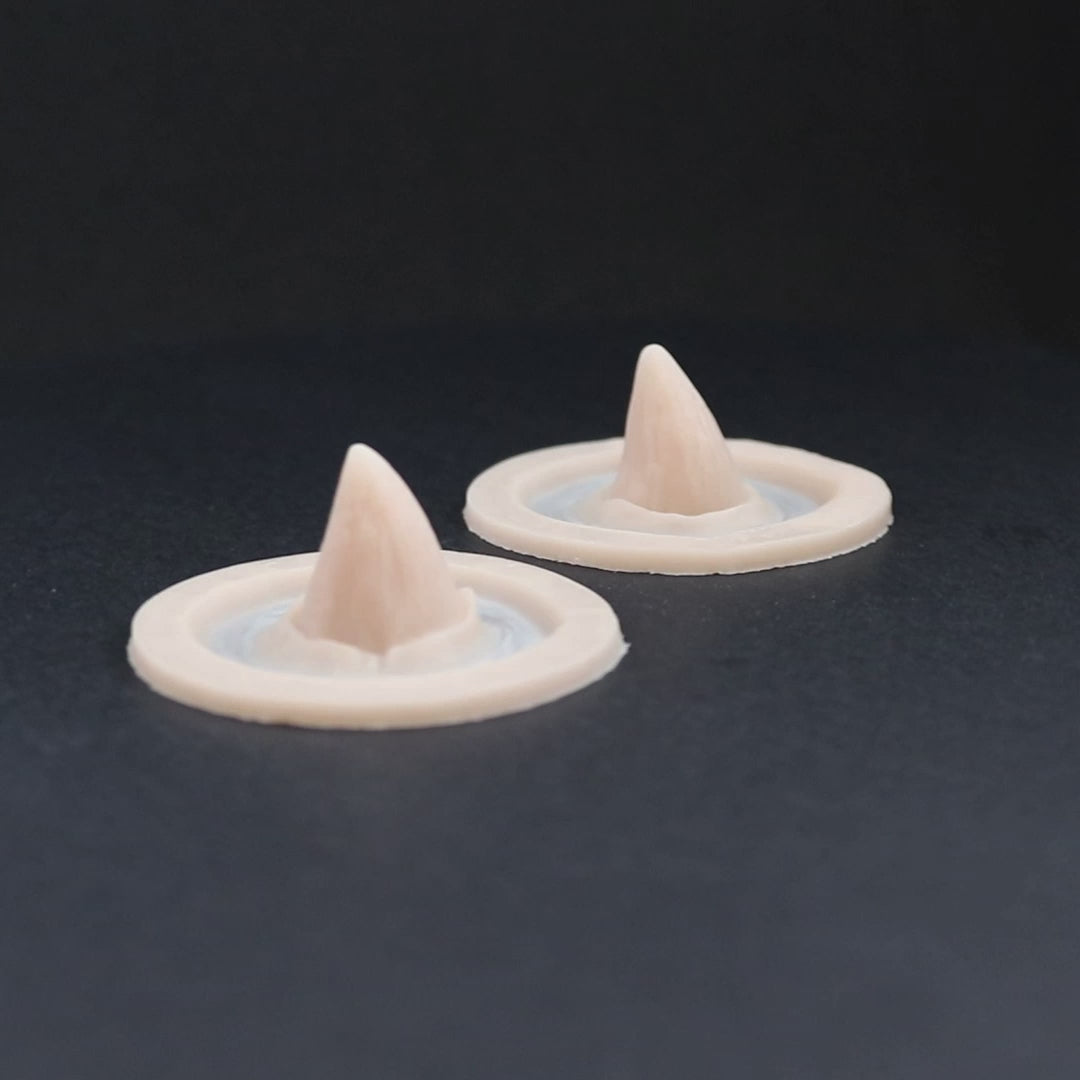 Small devil horns prosthetics in vanilla shade on a black turntable, slowly rotating.