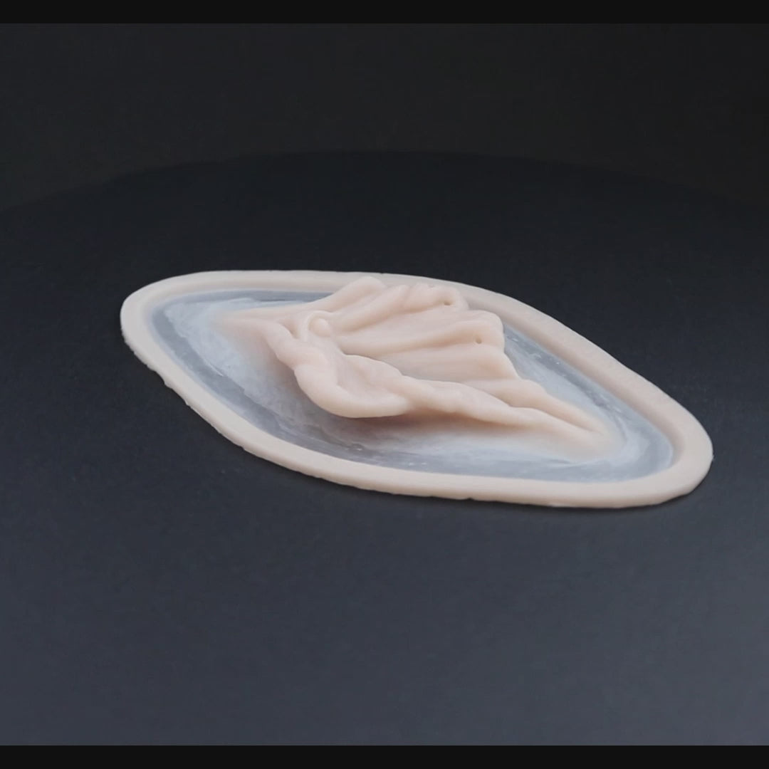 Flower neck piece prosthetic in vanilla shade on a black turntable, slowly rotating.