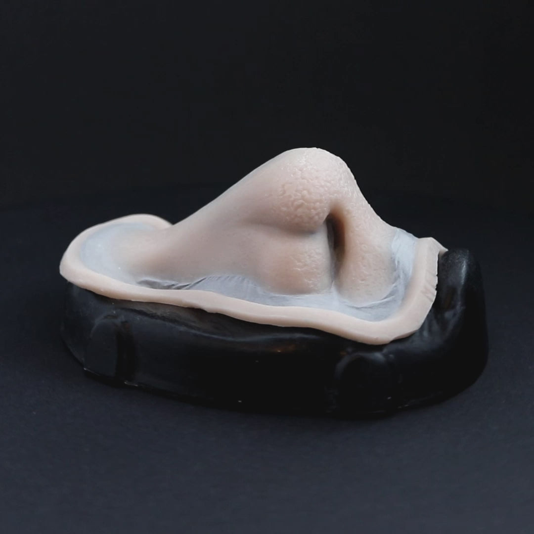 Satyr nose prosthetic in vanilla shade on a black turntable, slowly rotating.