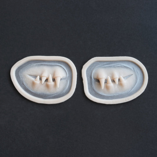Facial Fangs 2.0 - Silicone makeup prosthetic in vanilla shade on a black surface