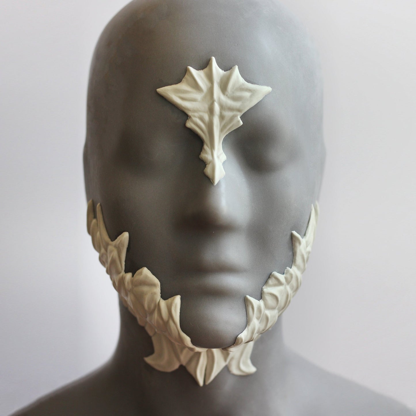 Mannequin wearing white facial scale prosthetics