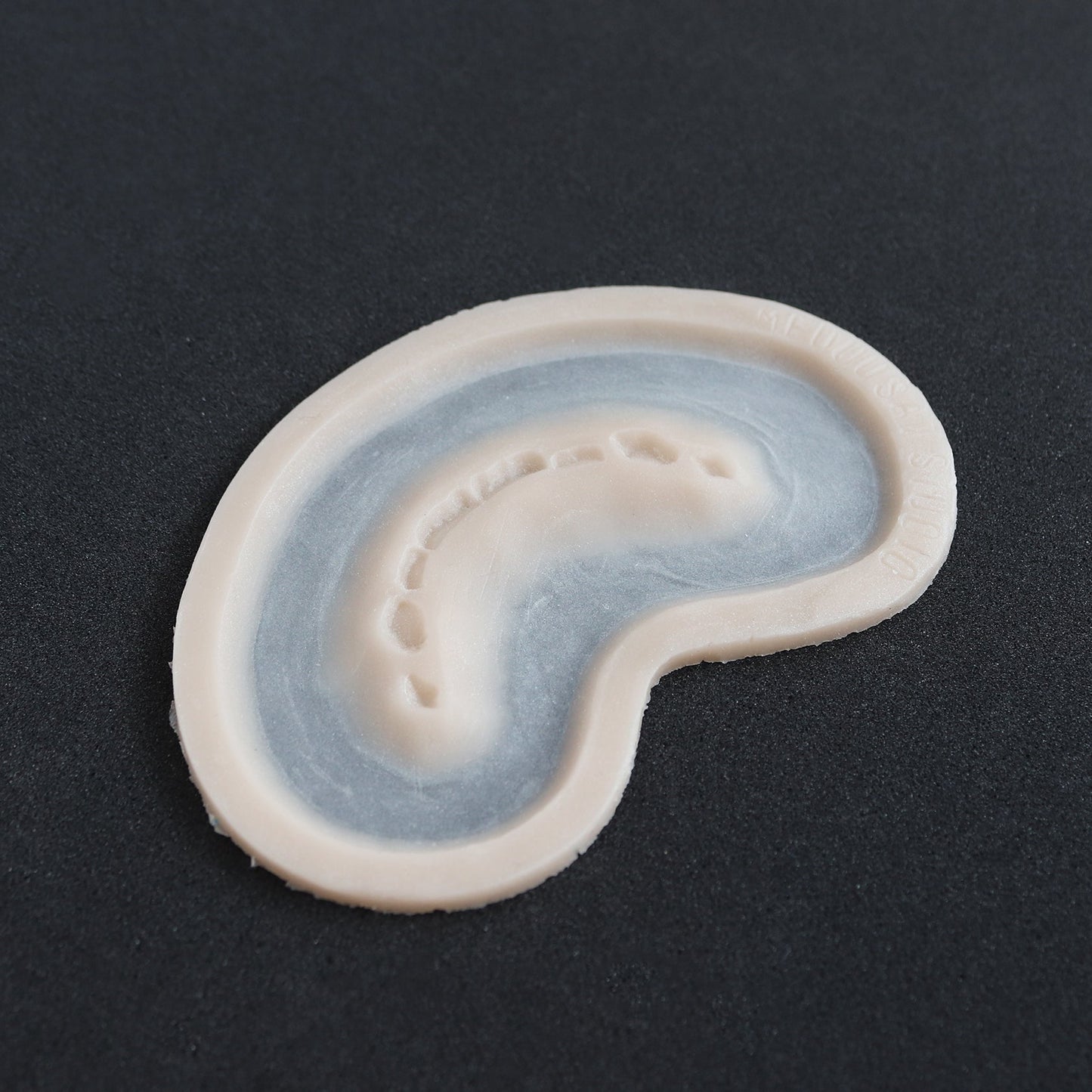 Half Bite - Silicone makeup prosthetic in vanilla shade on a black surface