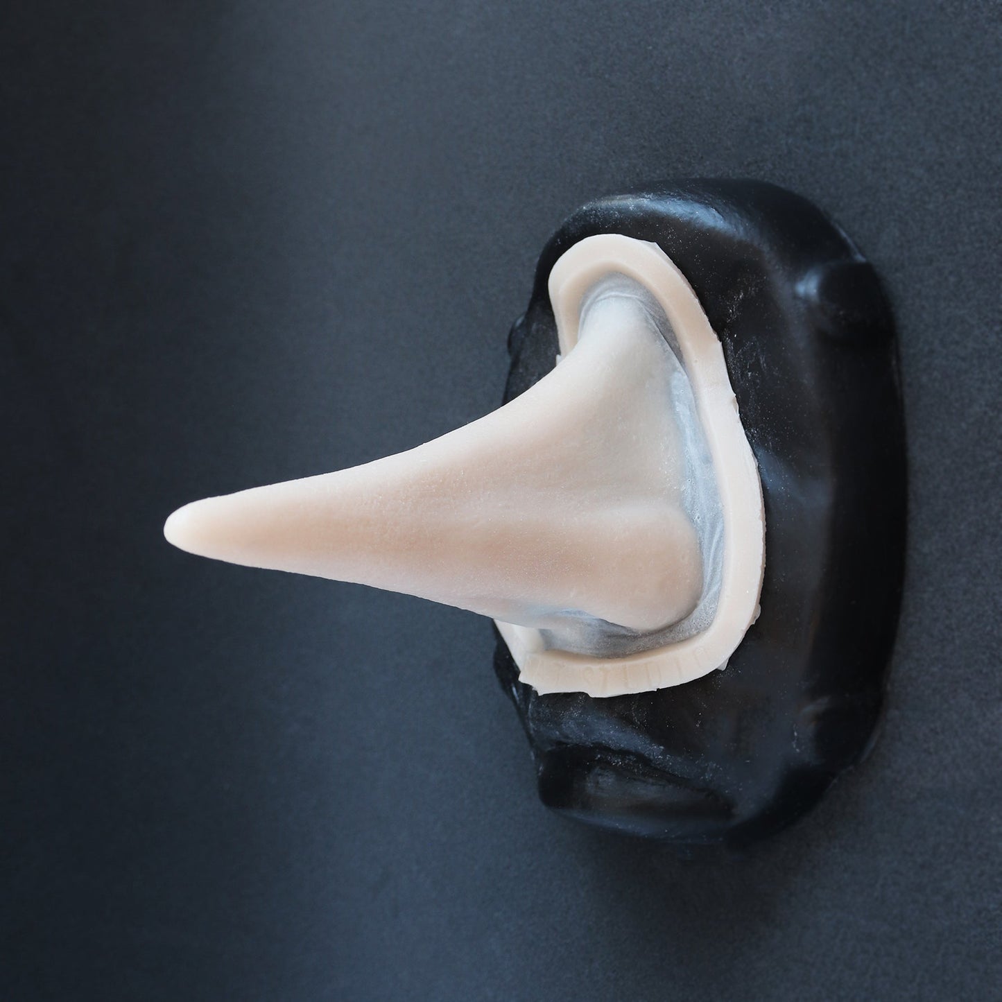 Long Pointy Nose - Silicone makeup prosthetic in vanilla shade on a black surface