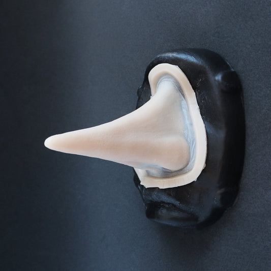 Long Pointy Nose - Silicone makeup prosthetic in vanilla shade on a black surface
