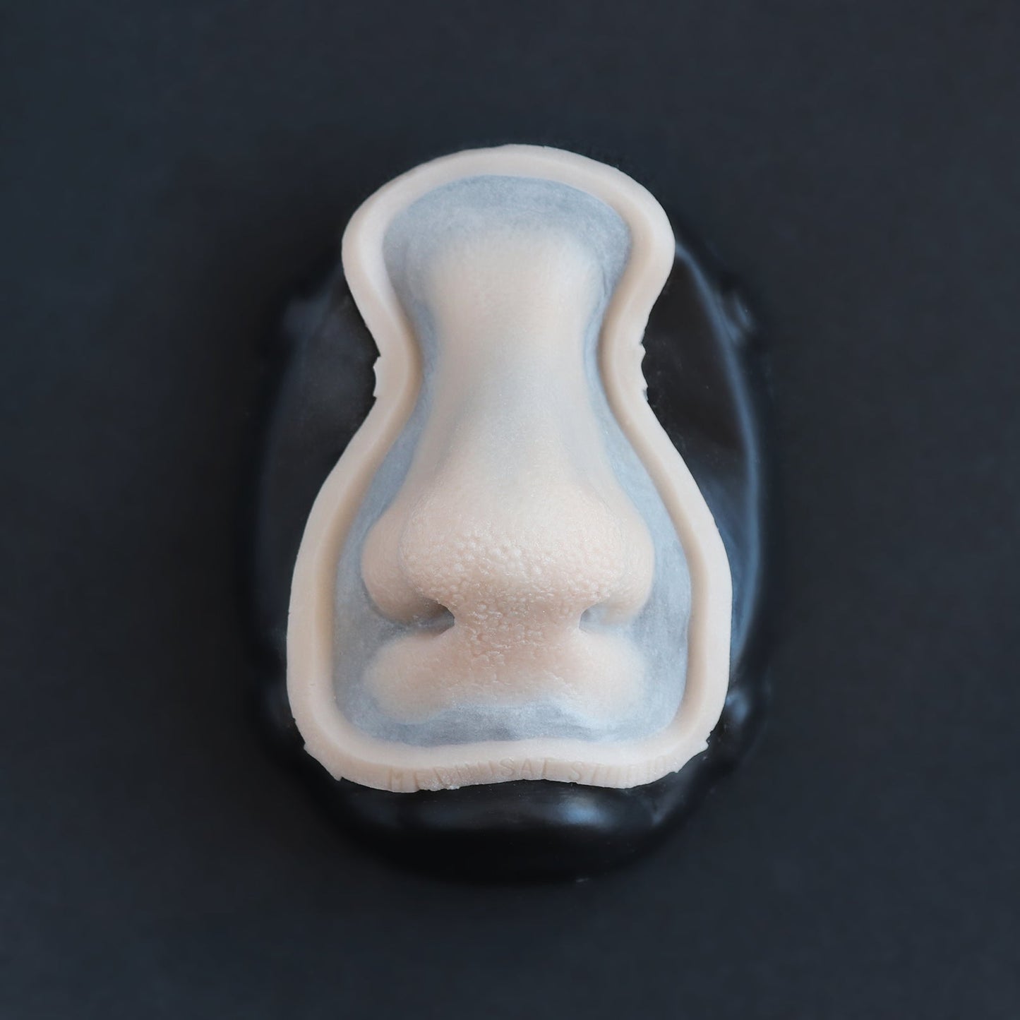 Satyr Nose - Silicone makeup prosthetic in vanilla shade on a black surface