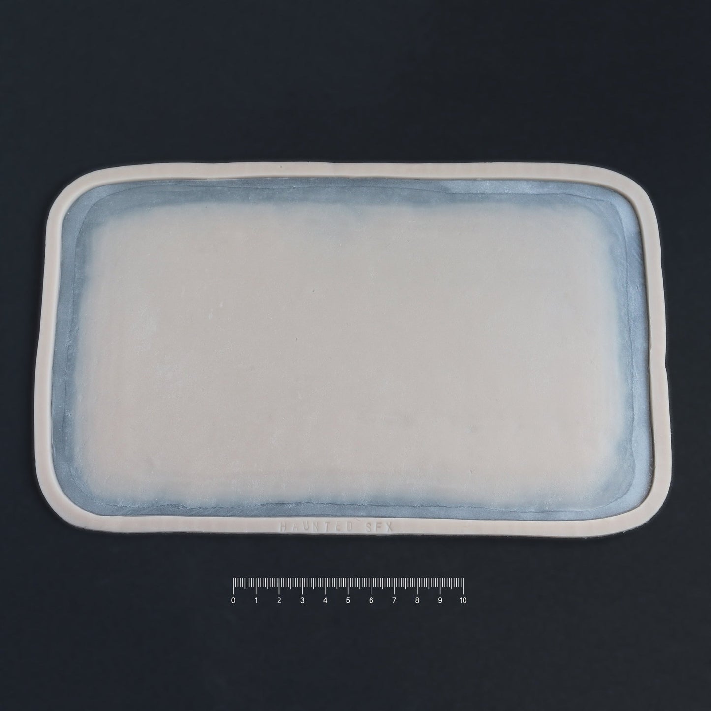 Regular Silicone Patch - Silicone makeup prosthetic in vanilla shade on a black surface with a ruler