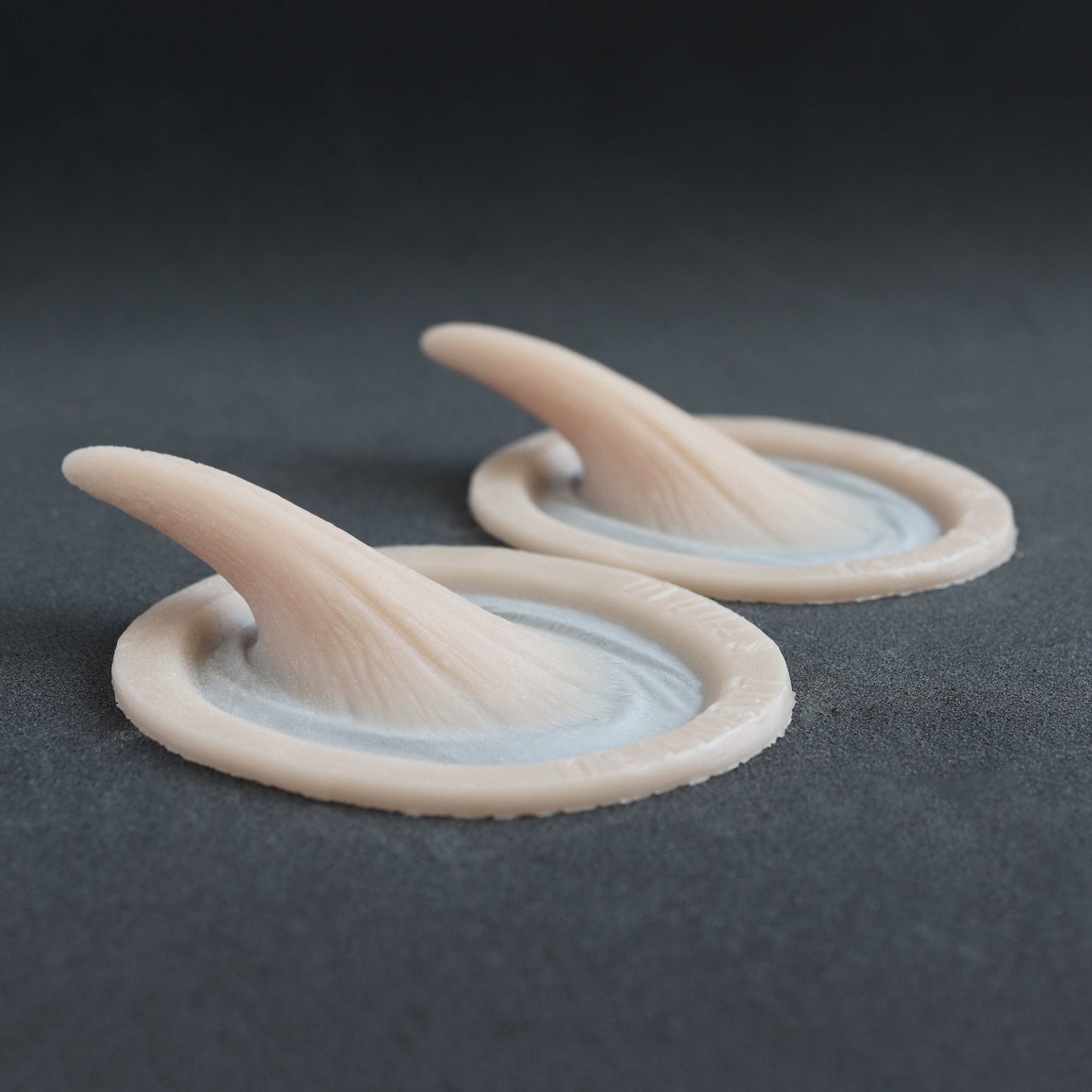 Small Vertical Horns (Pair) - Silicone makeup prosthetic in vanilla shade on a black surface