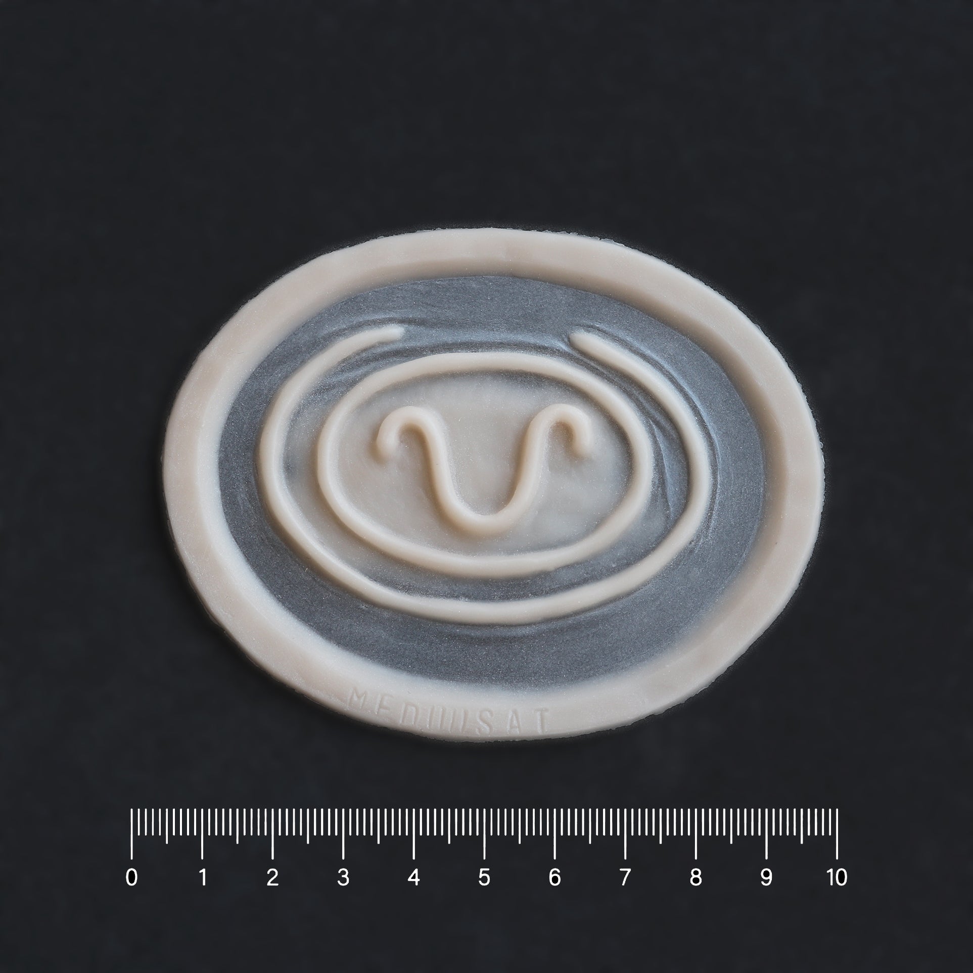 Stargate Goa'uld Mark - Silicone makeup prosthetic in vanilla shade on a black surface with a ruler