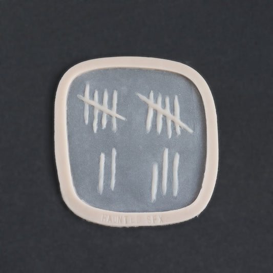 Tally Marks - Silicone makeup prosthetic in vanilla shade on a black surface