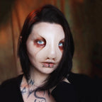 Woman with dark hair wearing a silicone makeup prosthetics mask and dark makeup