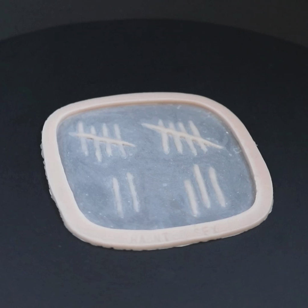 Tally mark prosthetic in vanilla shade on a black turntable, slowly rotating. 