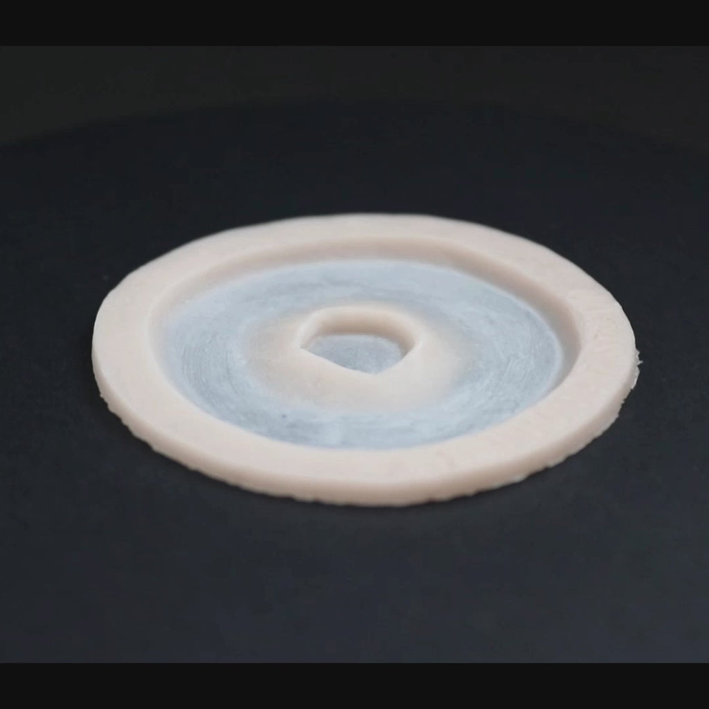 Gunshot Entry Wound prosthetic in vanilla shade on a black turntable, slowly rotating. 