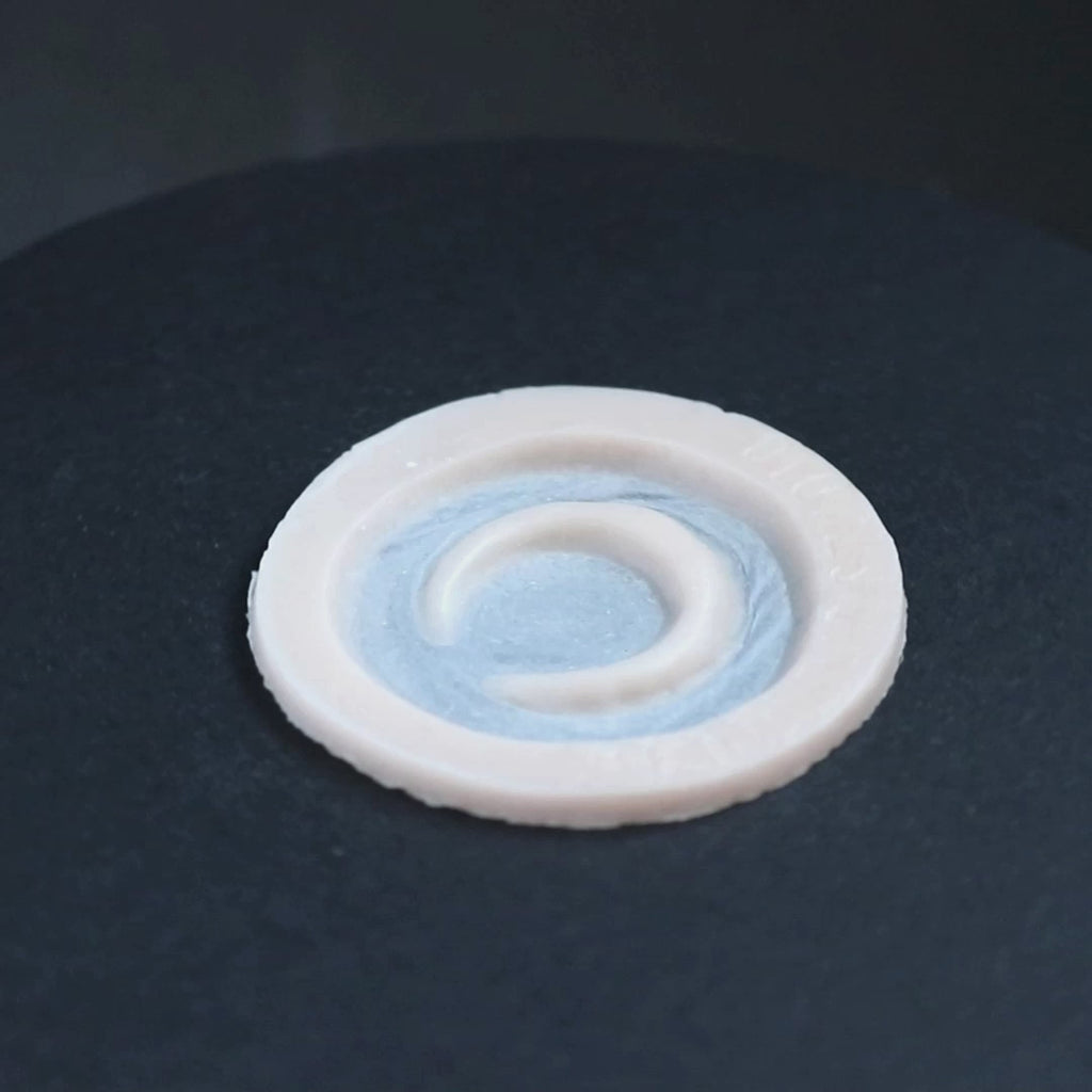 Small moon prosthetic in vanilla shade on a black turntable, slowly rotating. 