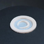 Small moon prosthetic in vanilla shade on a black turntable, slowly rotating. 