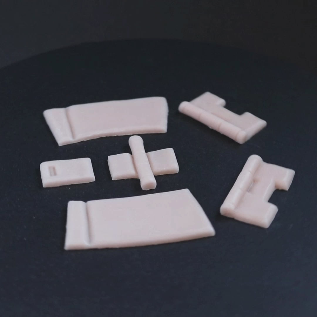 Silicone hinges in vanilla shade on a black turntable, slowly rotating. 