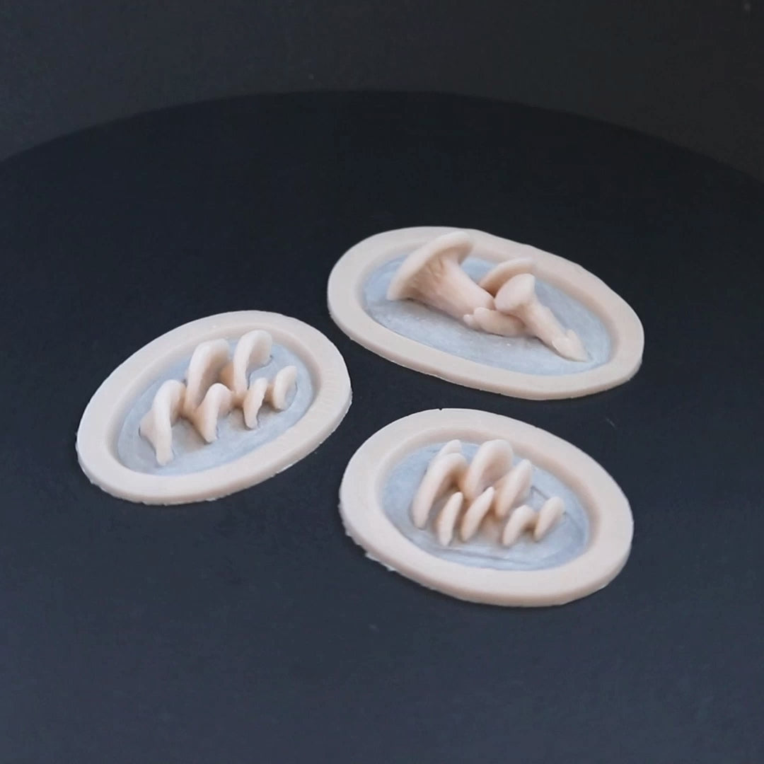Three mushroom prosthetics in vanilla shade on a black turntable, slowly rotating. 