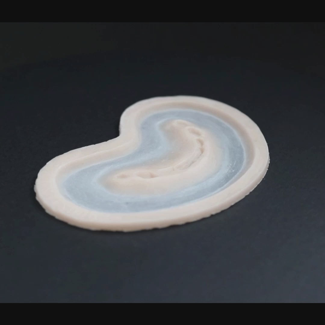 Half bite prosthetic in vanilla shade on a black turntable, slowly rotating. 