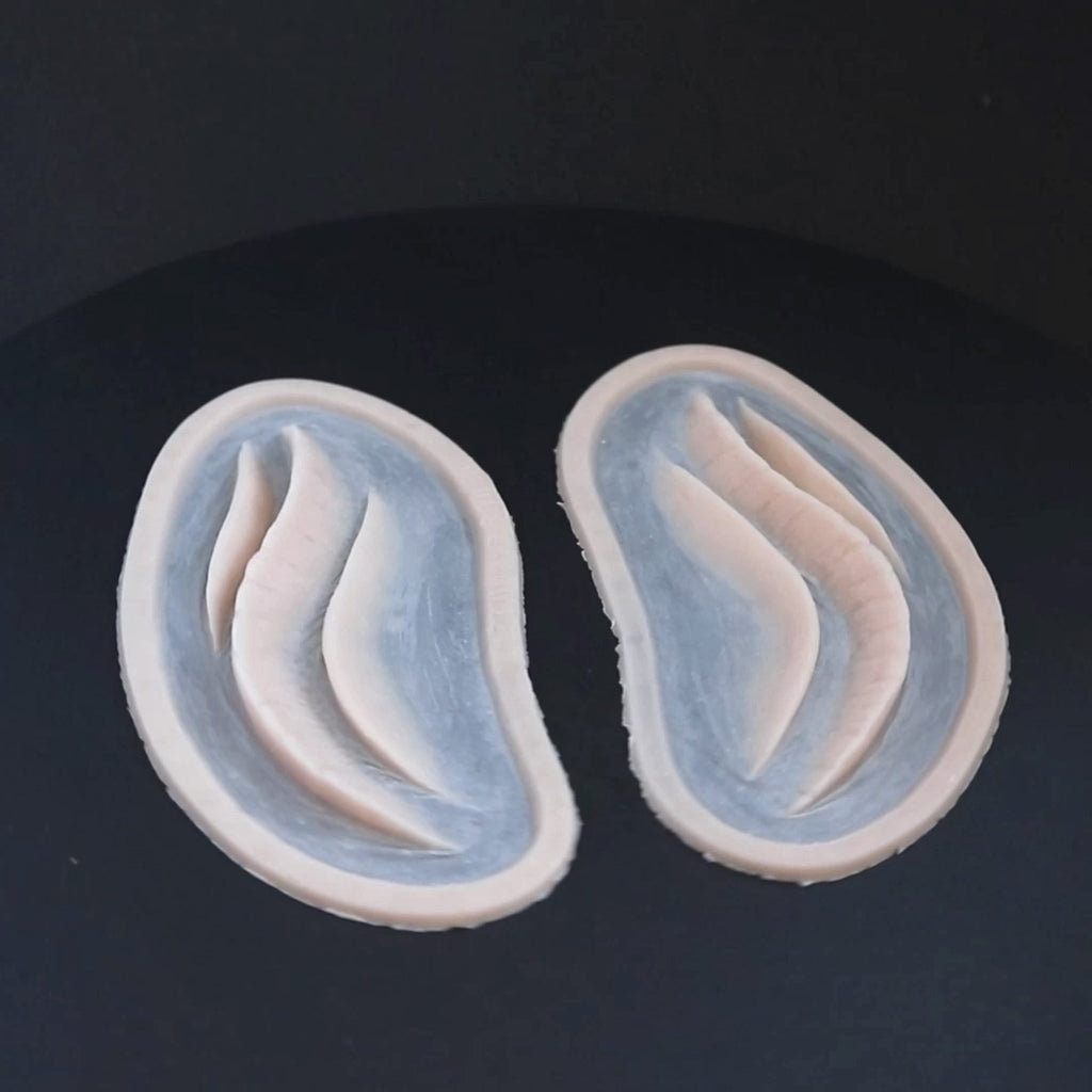 A pair of mermaid gills prosthetics in vanilla shade on a black turntable, slowly rotating. 