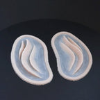 A pair of mermaid gills prosthetics in vanilla shade on a black turntable, slowly rotating. 