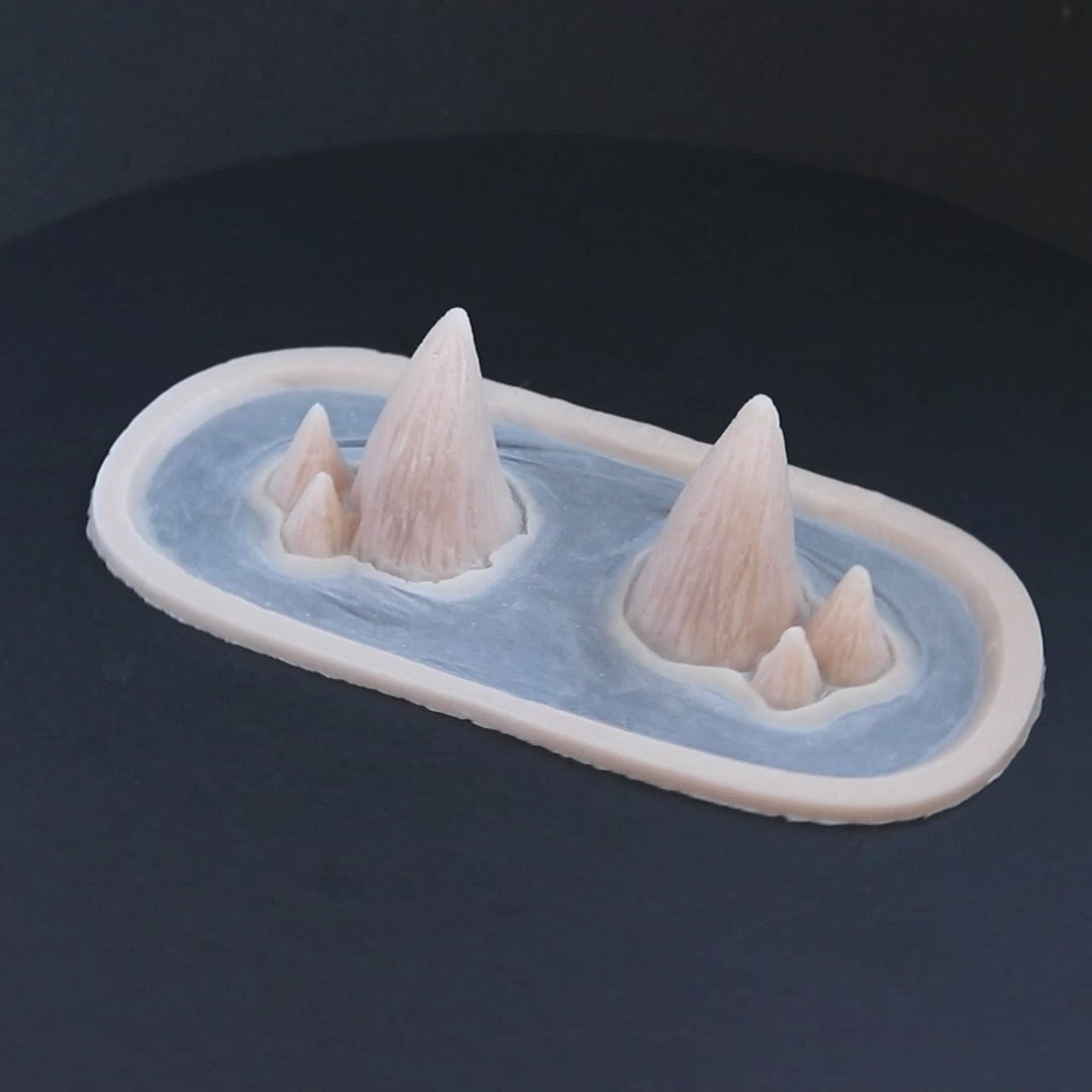 Triple devil horns prosthetics in vanilla shade on a black turntable, slowly rotating. 