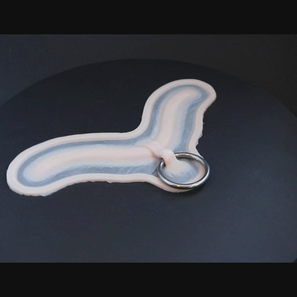 Subdermal choker, with steel ring, prosthetic in vanilla shade on a black turntable, slowly rotating. 