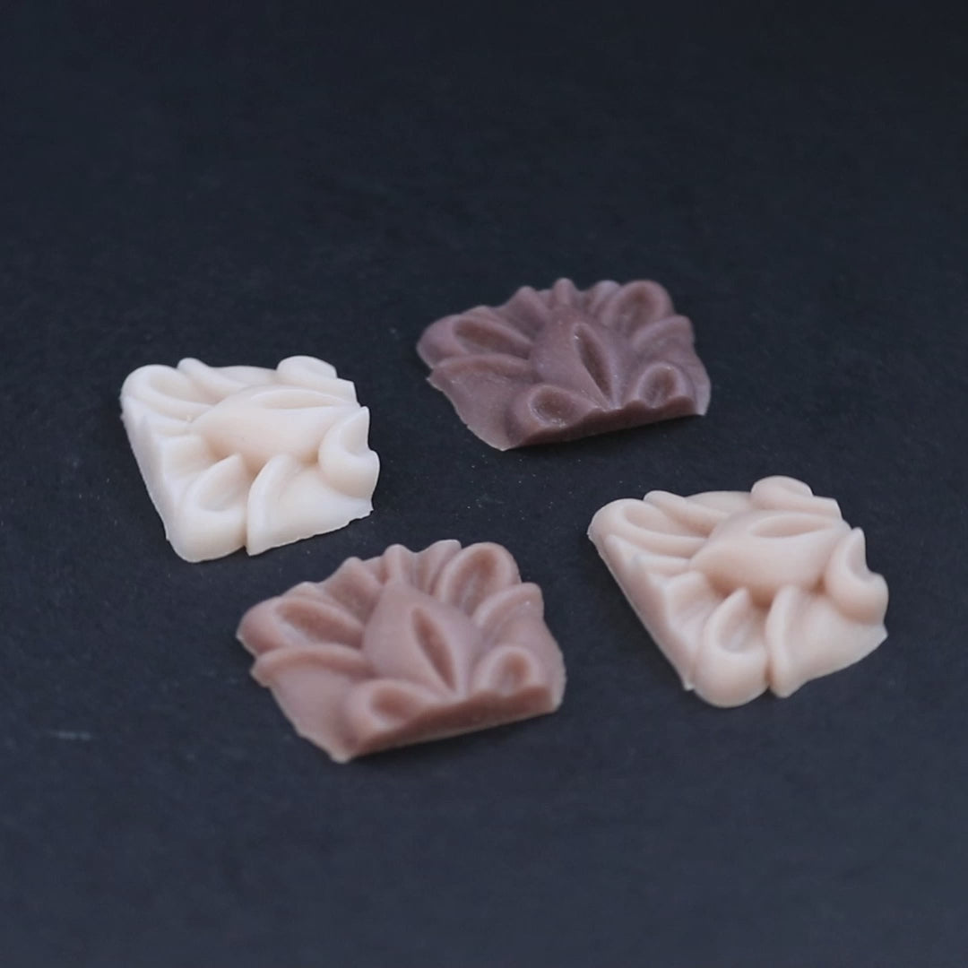 Four pieces of silicone in different skin tones on a black turntable, slowly rotating. 