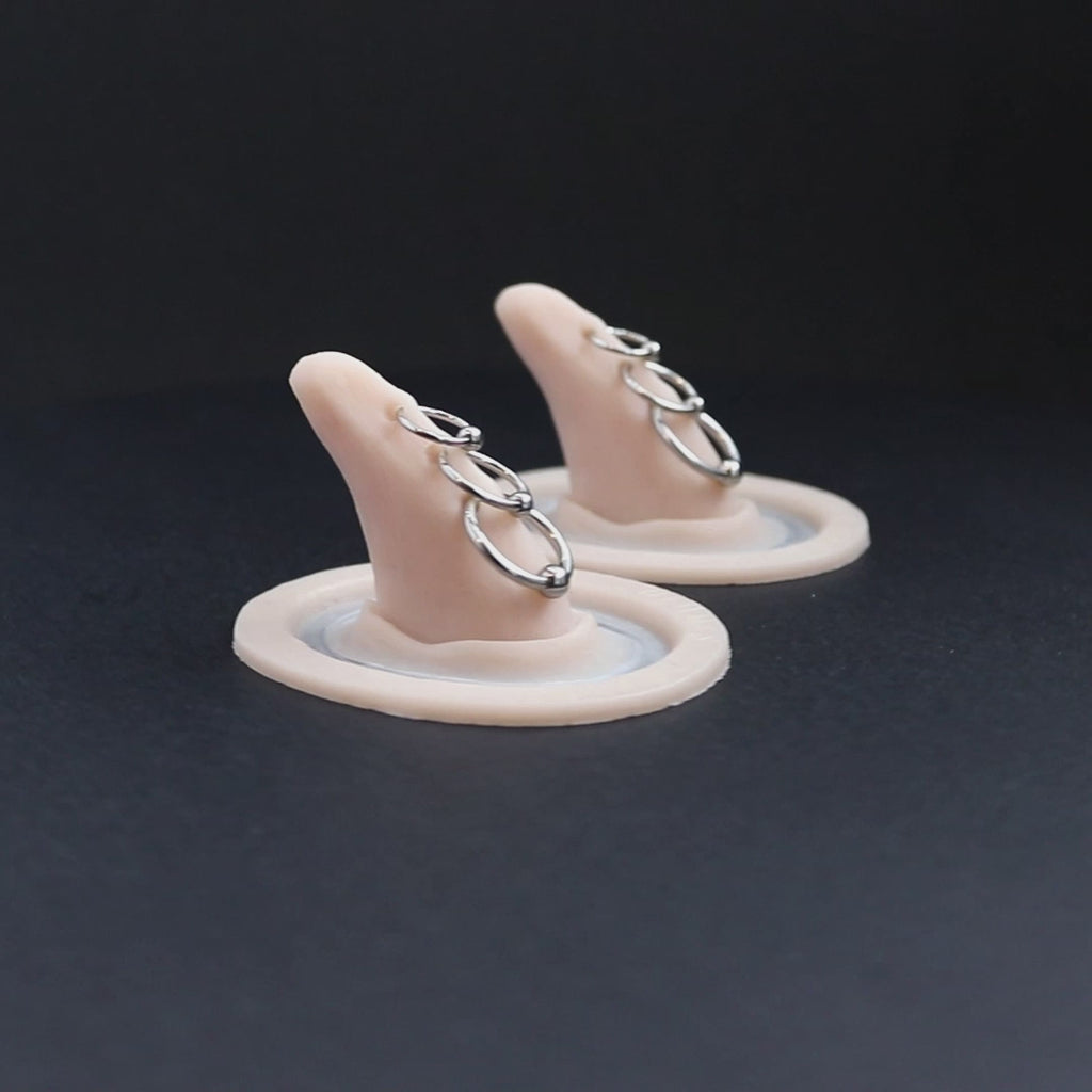 Pair of triple pierced horns prosthetics in vanilla shade on a black turntable, slowly rotating. 