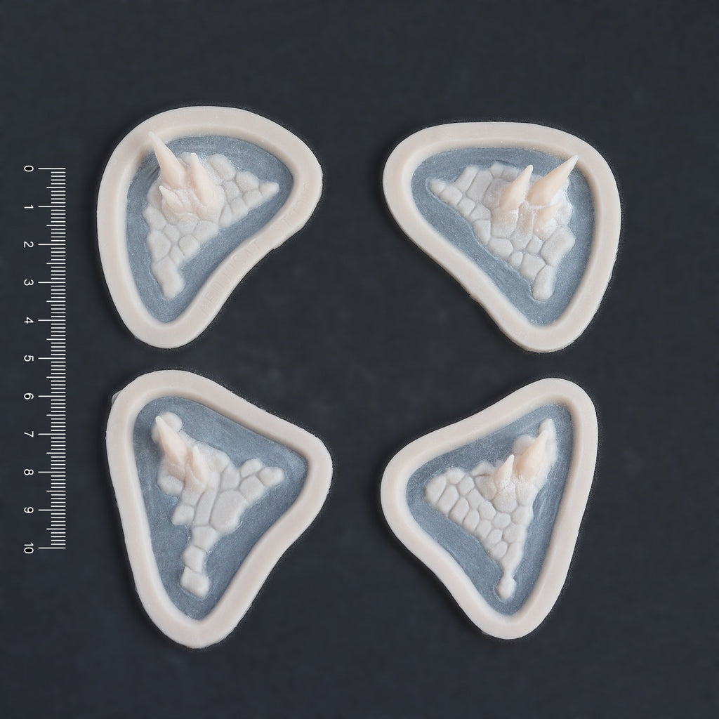 Alligator Scales temple and cheek pieces in vanilla shade on a black surface with a ruler.