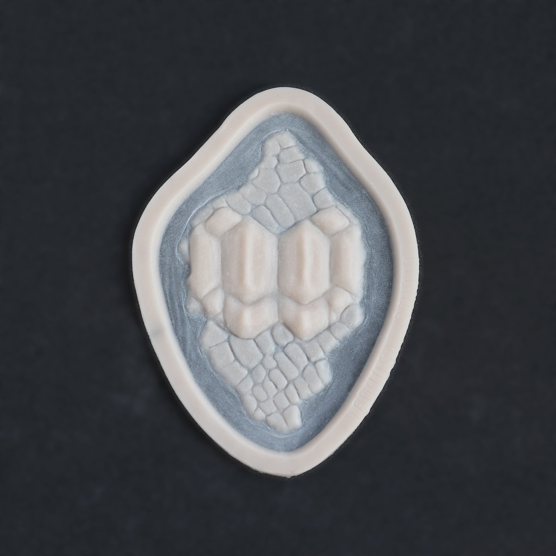 Alligator Scales neck piece in vanilla shade on a black surface.