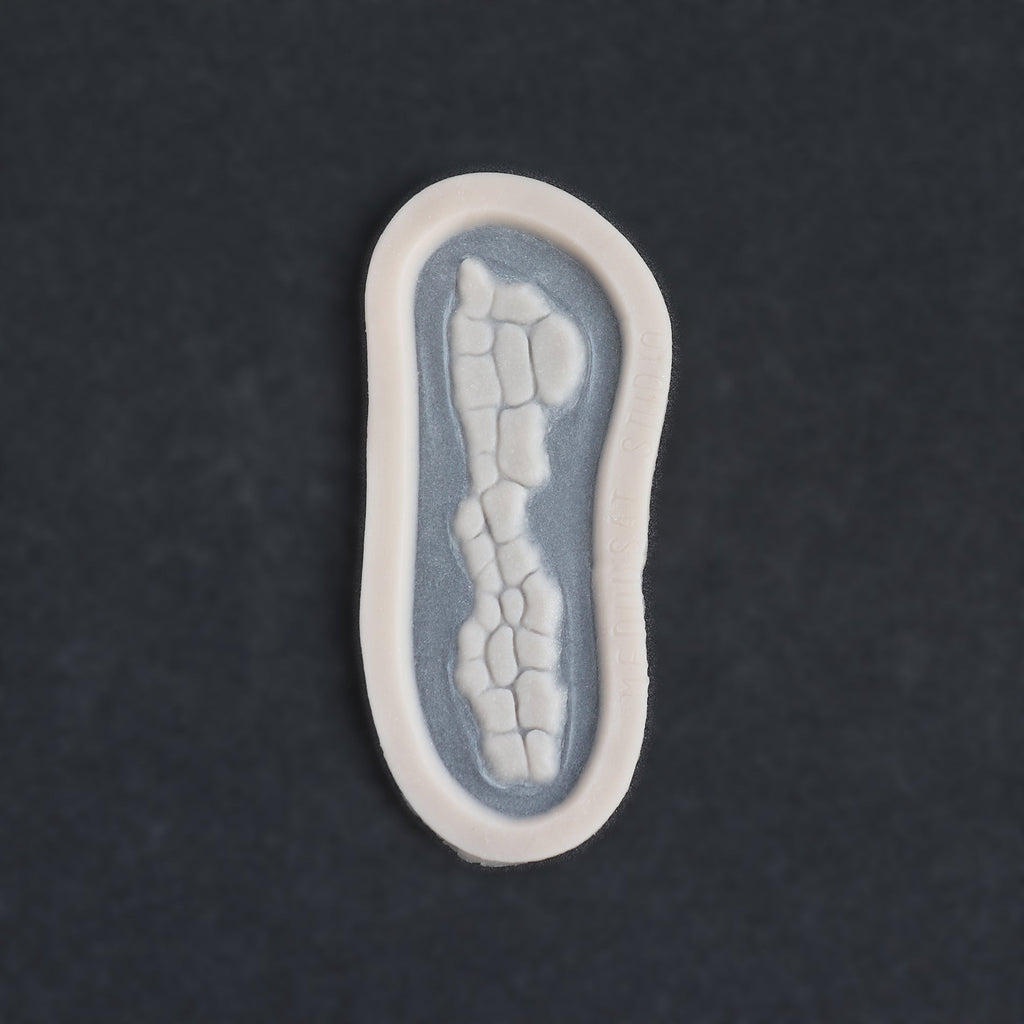 Alligator Scales nose piece in vanilla shade on a black surface.