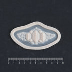 Alligator Scales chin piece in vanilla shade on a black surface with a ruler.