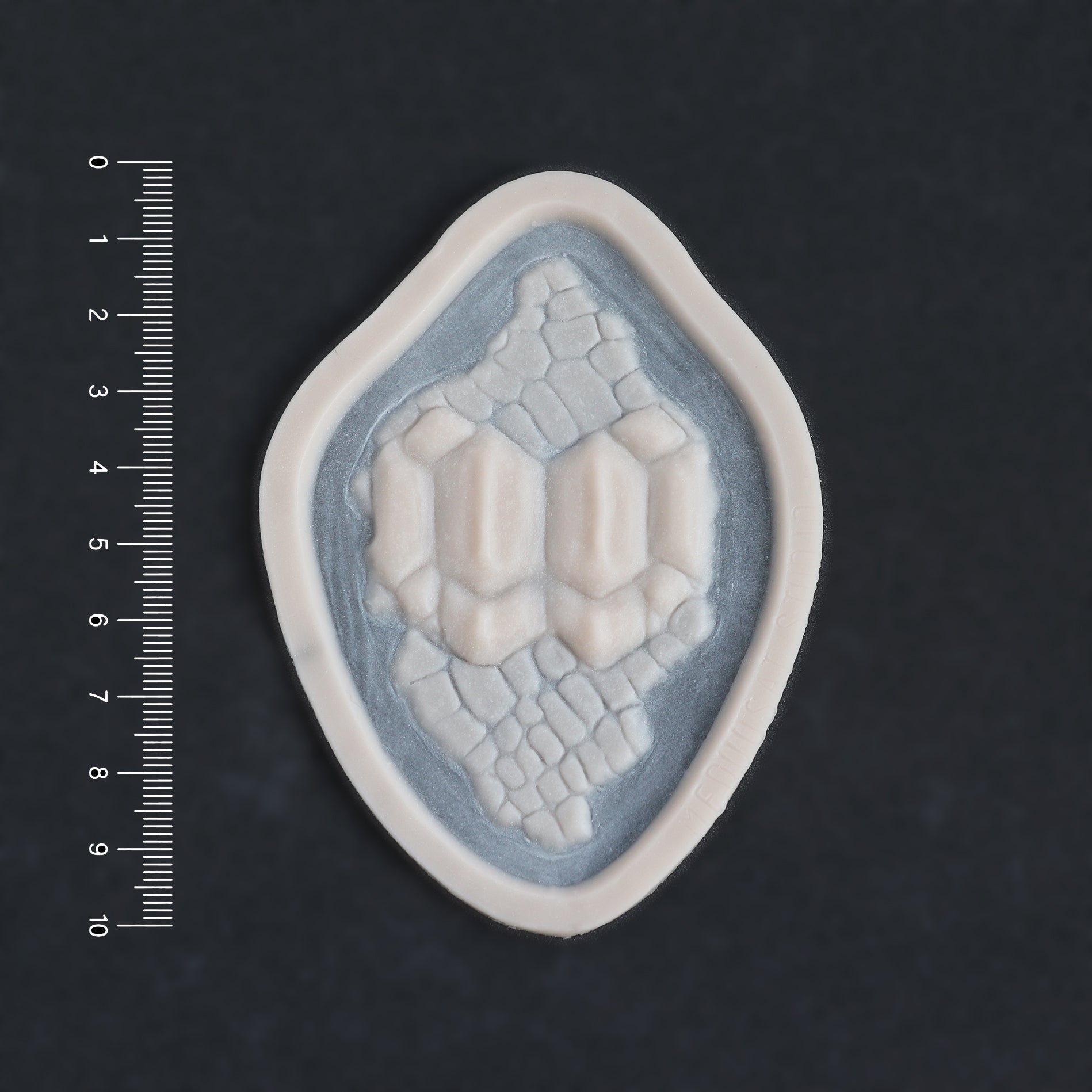 Alligator Scales neck piece in vanilla shade on a black surface with a ruler.