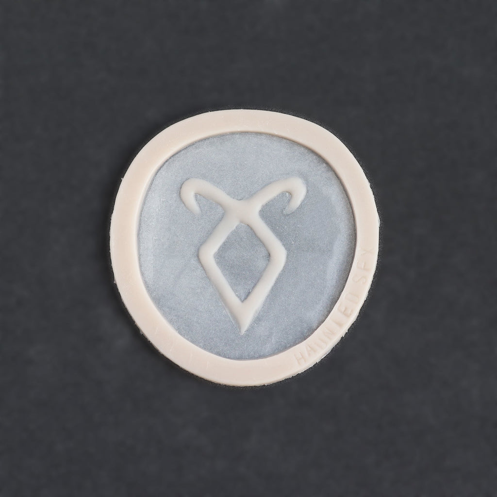 Angel Rune Scarification in vanilla shade on a black surface.