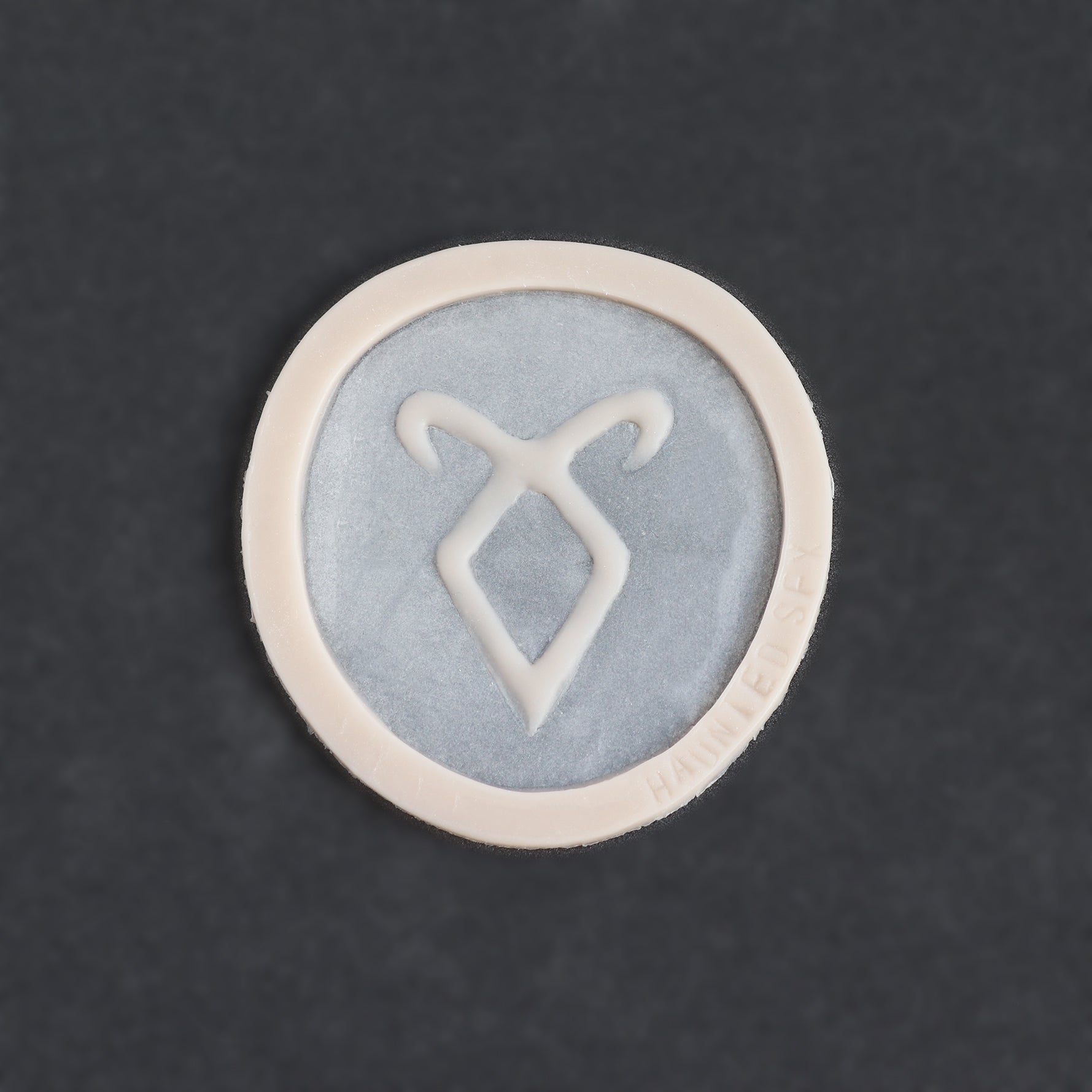 Angel Rune Scarification in vanilla shade on a black surface.