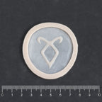 Angel Rune Scarification in vanilla shade on a black surface with a ruler.