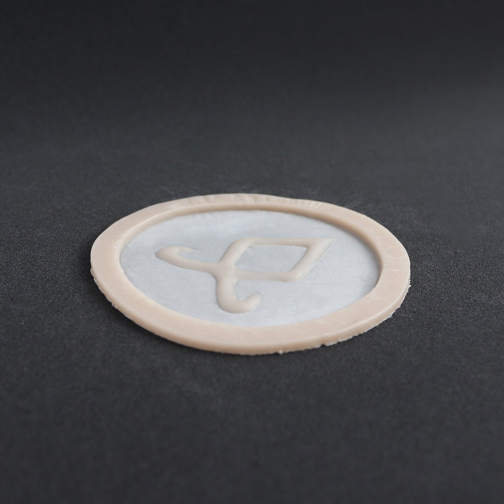 Angel Rune Scarification in vanilla shade at a steep angle on a black surface.