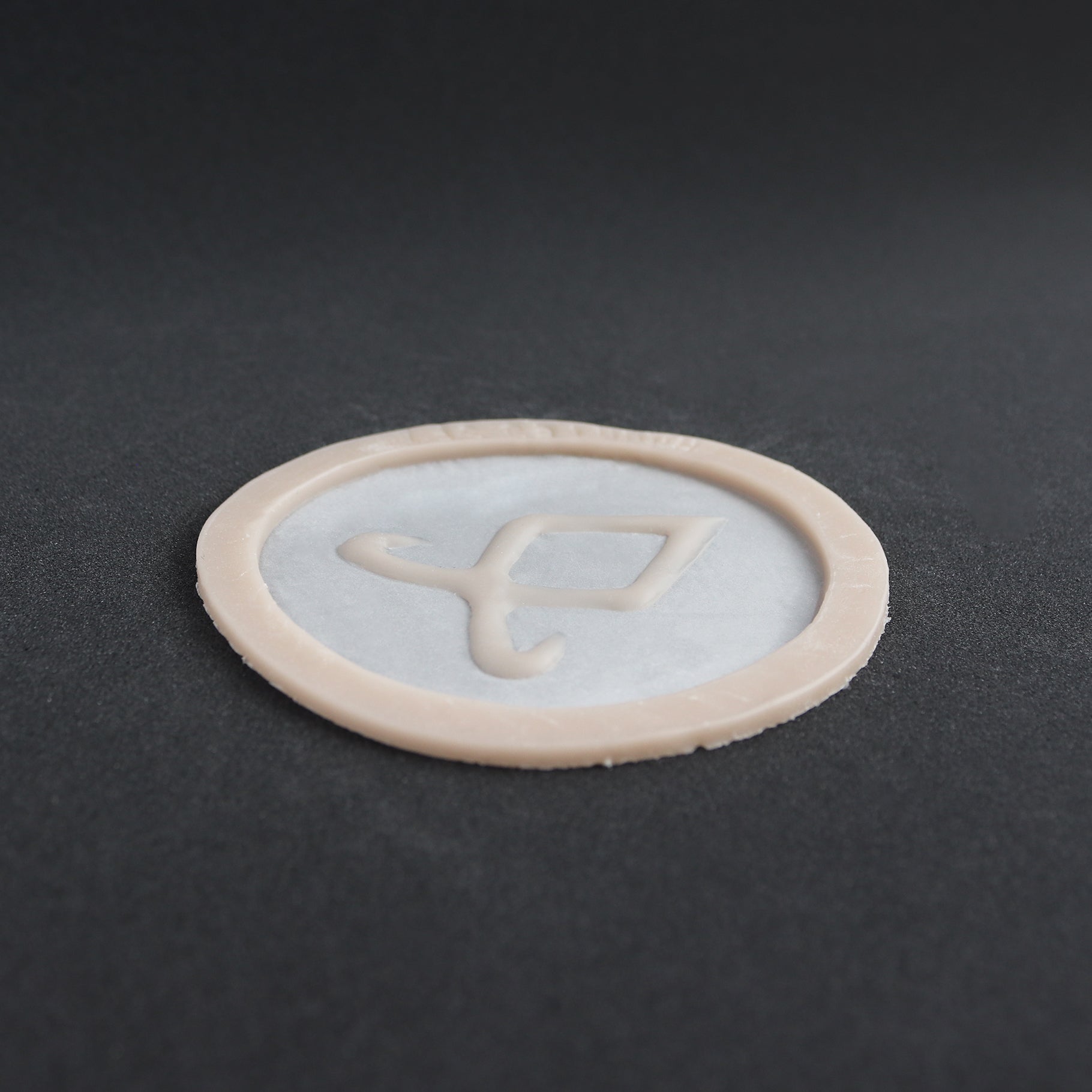 Angel Rune Scarification in vanilla shade at a steep angle on a black surface.