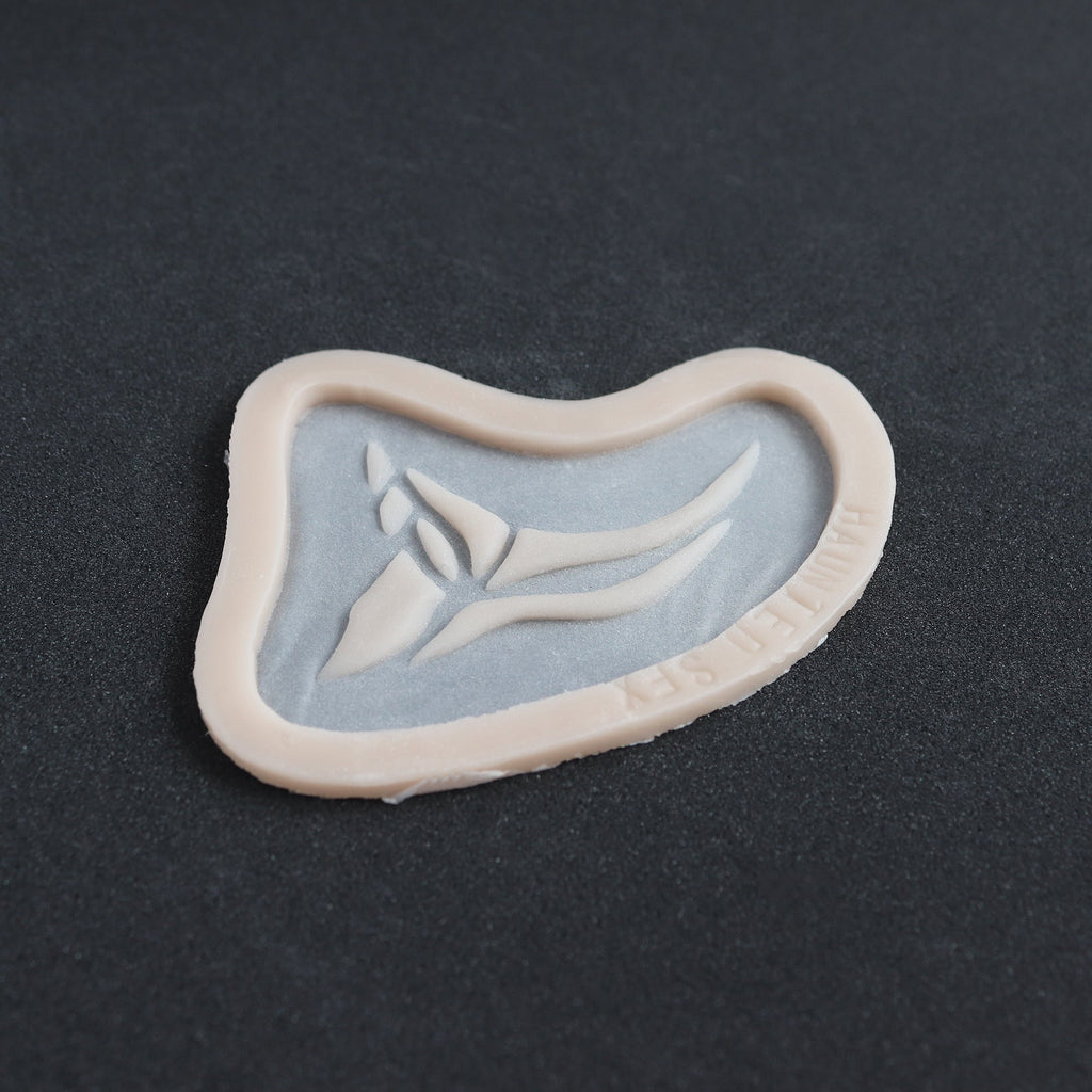 Anubis Mark - Silicone makeup prosthetic in vanilla shade on a black surface