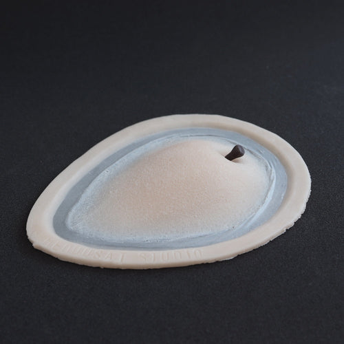 Apple Cheek prosthetic in vanilla shade on a black surface at an angle.