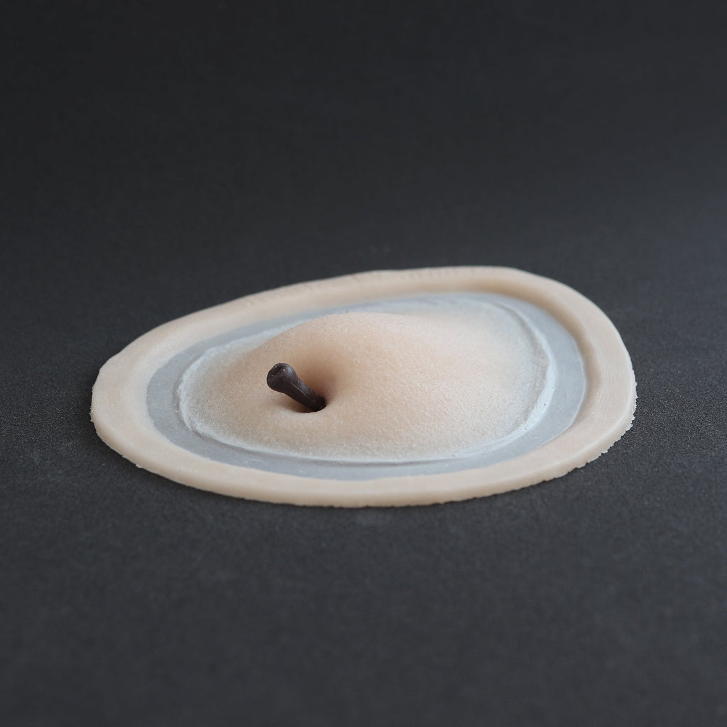 Apple Cheek prosthetic in vanilla shade on a black surface at a steep angle.