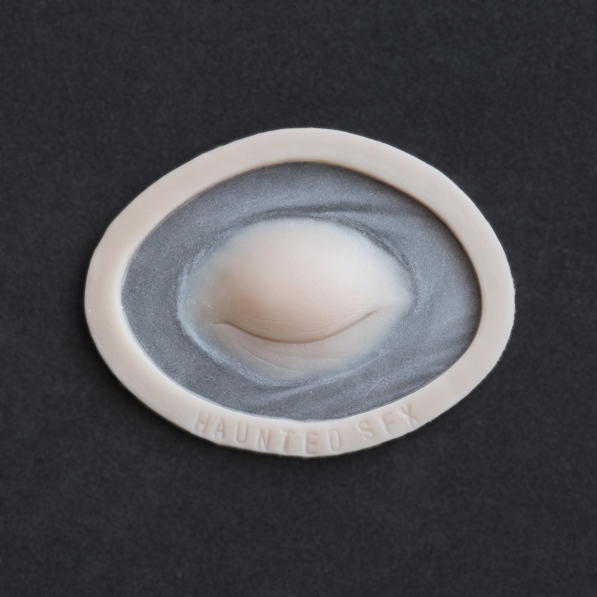 Closed Third Eye - Silicone makeup prosthetic in vanilla shade on a black surface