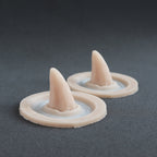 Crooked Horns (Pair) - Silicone makeup prosthetic in vanilla shade on a black surface