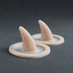 Crooked Horns (Pair) - Silicone makeup prosthetic in vanilla shade on a black surface