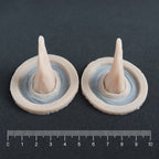 Crooked Horns (Pair) - Silicone makeup prosthetic in vanilla shade on a black surface with a ruler