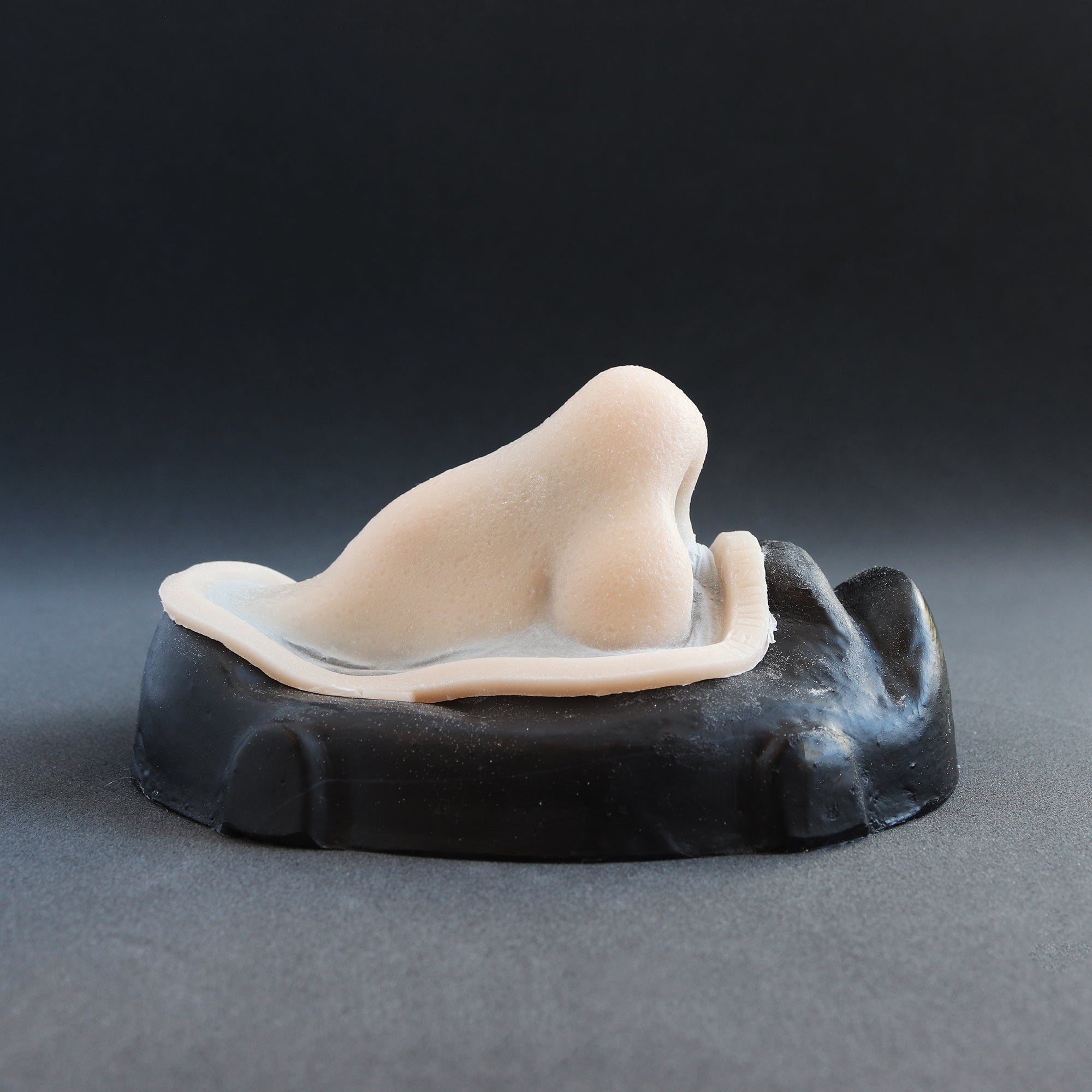 Crooked Nose - Silicone makeup prosthetic in vanilla shade on a black surface