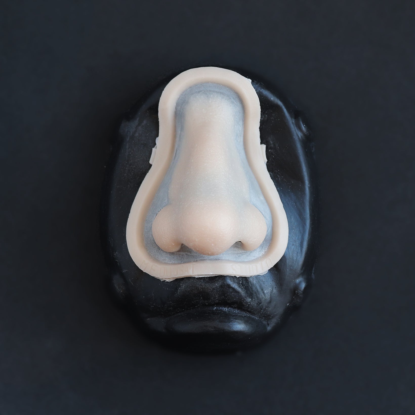 Crooked Nose - Silicone makeup prosthetic in vanilla shade on a black surface
